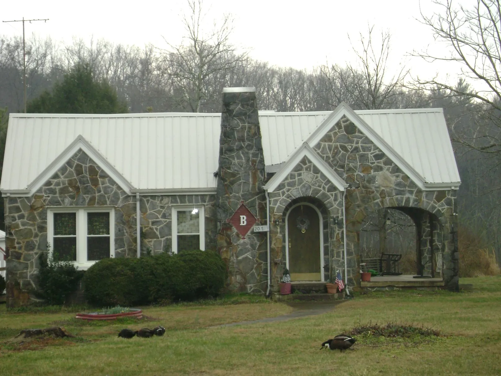 White metal roof on a stone cottage with steep gables in Hillsboro