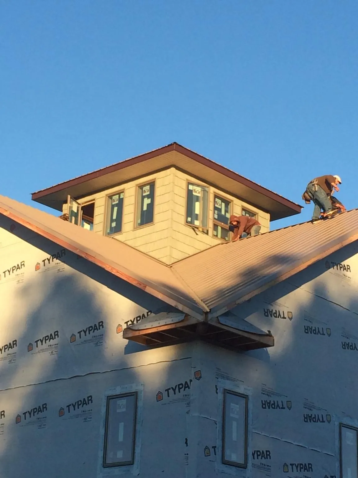 Roofers working around a rooftop cupola on a new metal roof at sunset — Roof Waterproofing in Hillsboro by Roofing Brothers